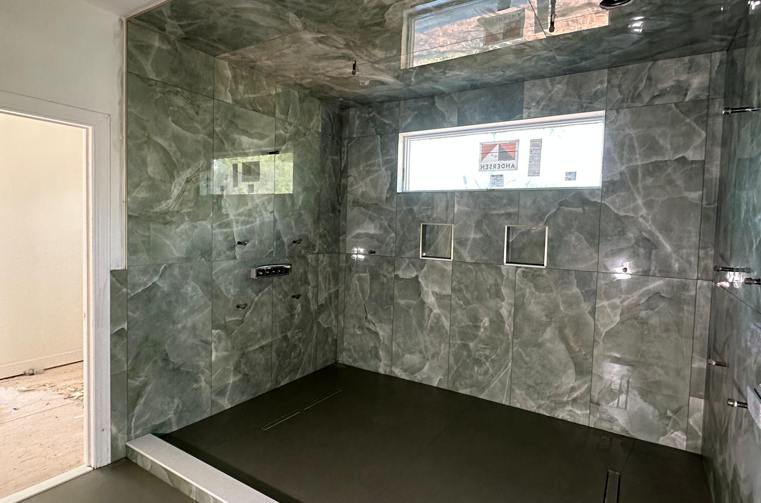 Finished dark green marble shower with recessed niche by Silcam Tile