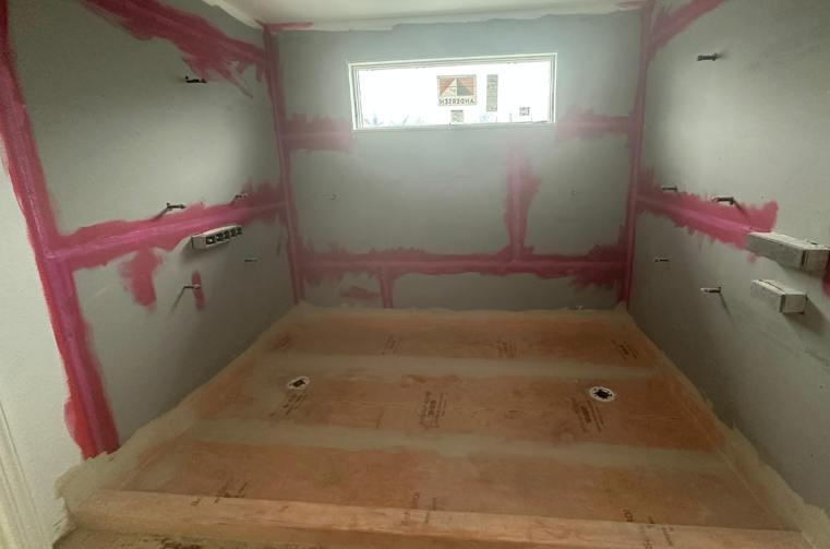 Shower walls with red waterproofing membrane applied before tiling