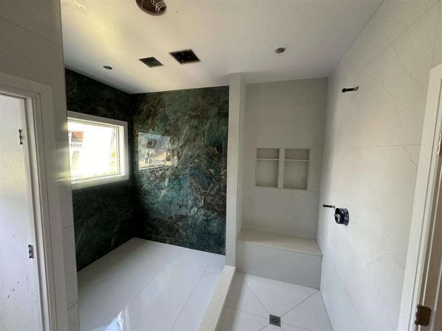 Dark green marble walk-in shower with frameless glass by Silcam Tile Installation, New Jersey